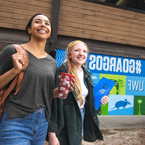 Two students stand near the Commons mural